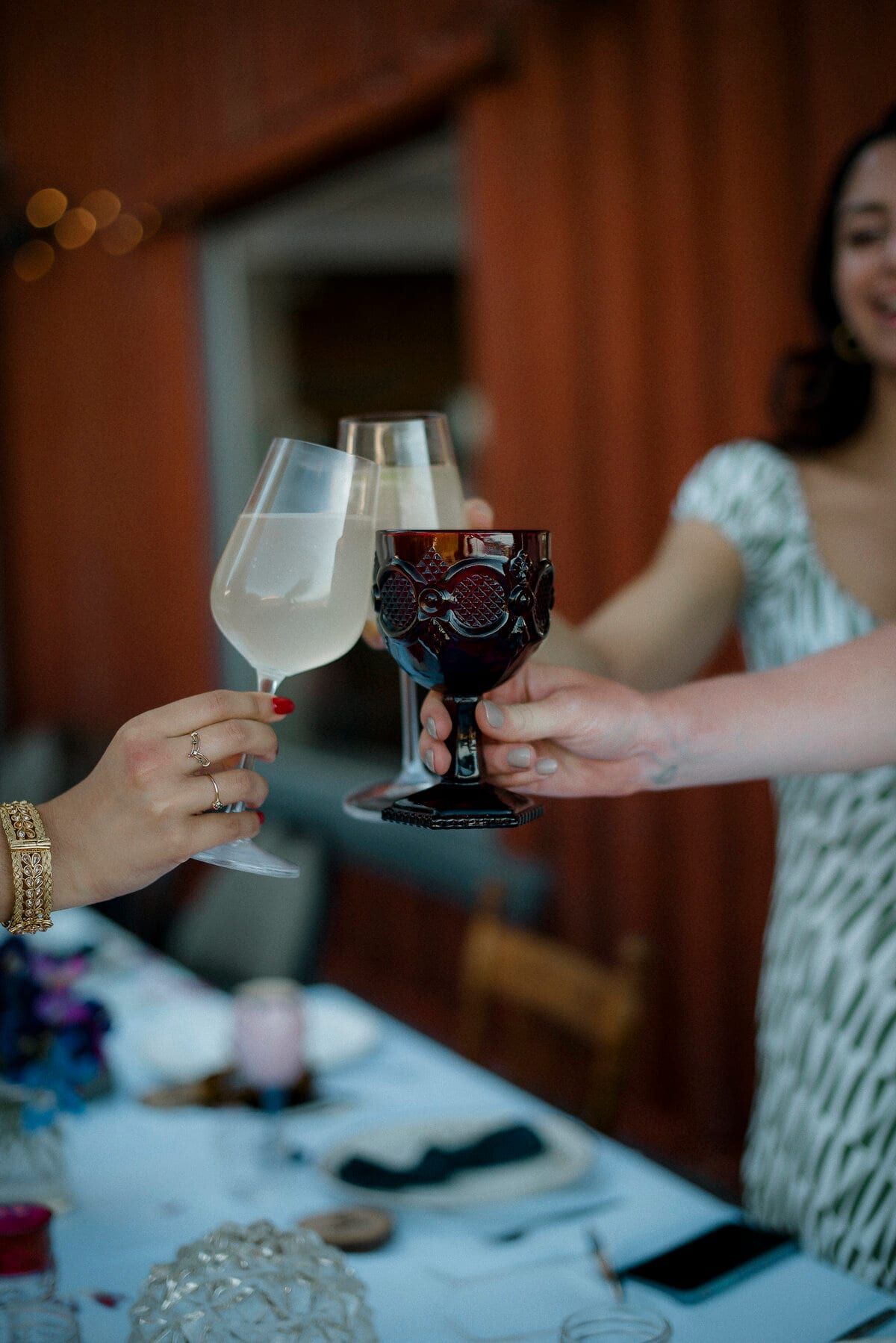 Wine glass and purple goblet raised in a toast across the table