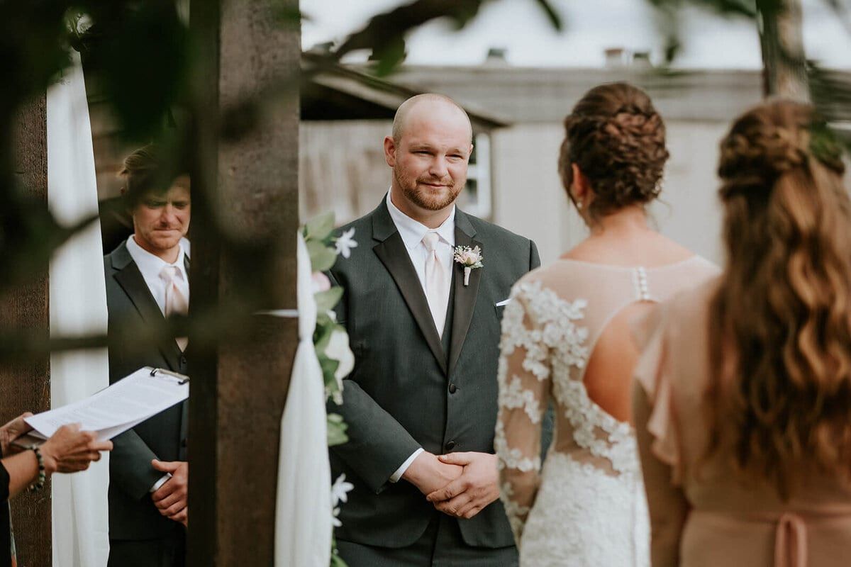 Groom smiling warmly at his bride during the outdoor ceremony