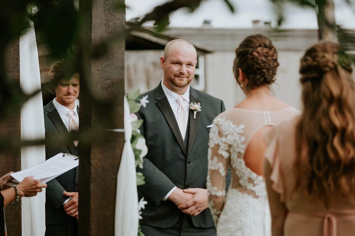 Groom smiling warmly at his bride during the outdoor ceremony