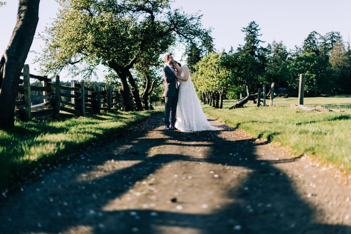 Newlyweds pausing for a kiss beneath old orchard trees