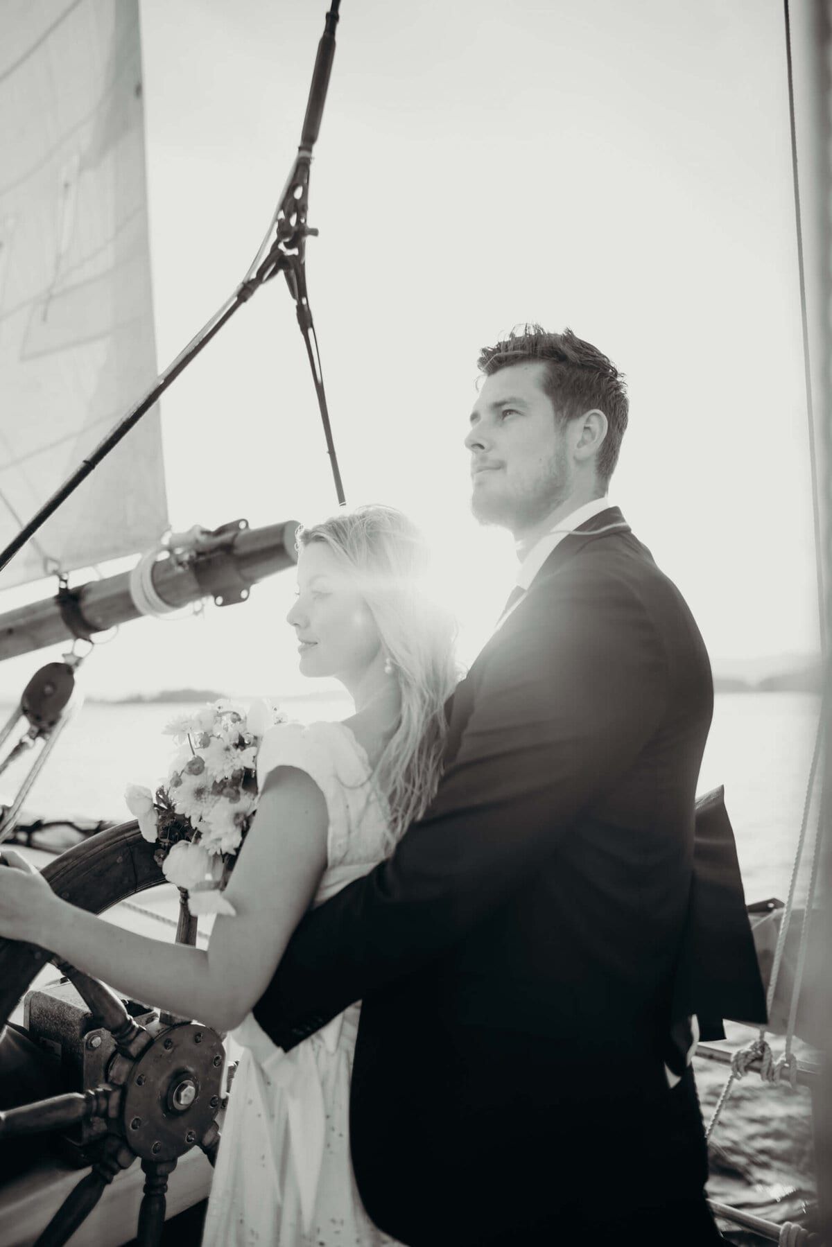 Sunlight flaring behind a couple steering the ship together