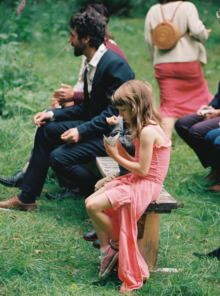 Young guest in a pink dress perched on a wooden bench