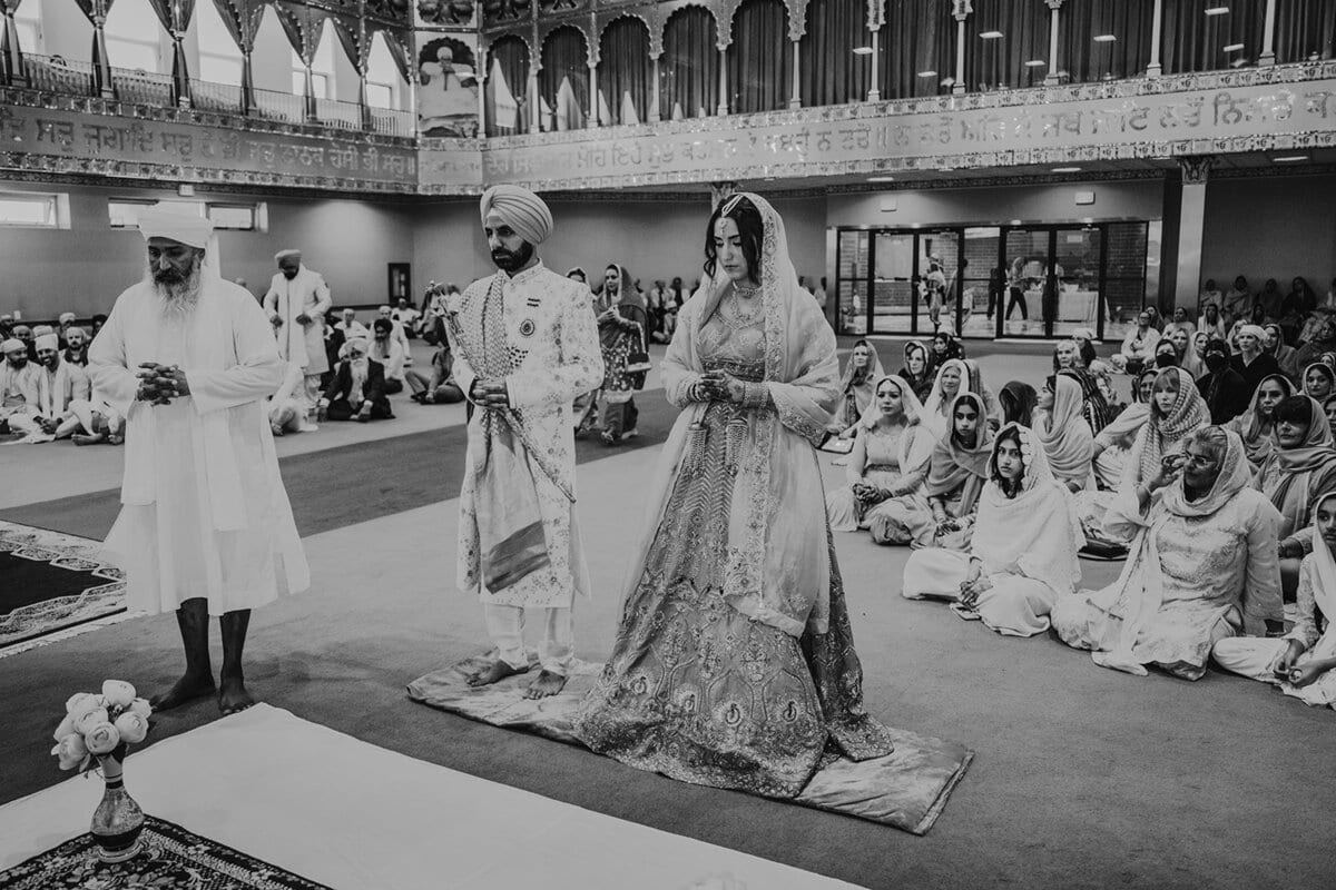Sikh couple standing before the congregation in a gurdwara ceremony