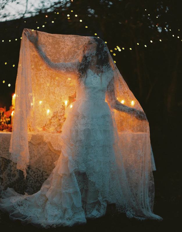 Lace-veiled bride at a candlelit table strung with fairy lights