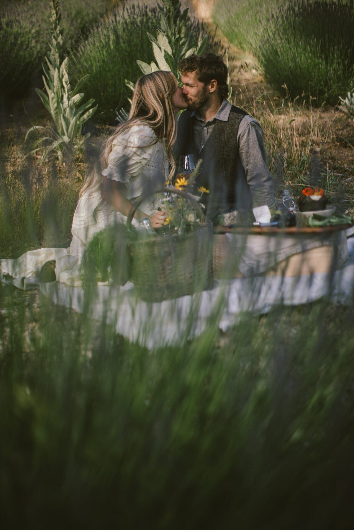 Couple kissing over a picnic spread in the lavender field