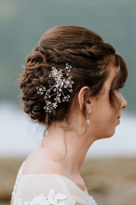 Braided bridal updo pinned with a crystal flower hairpiece