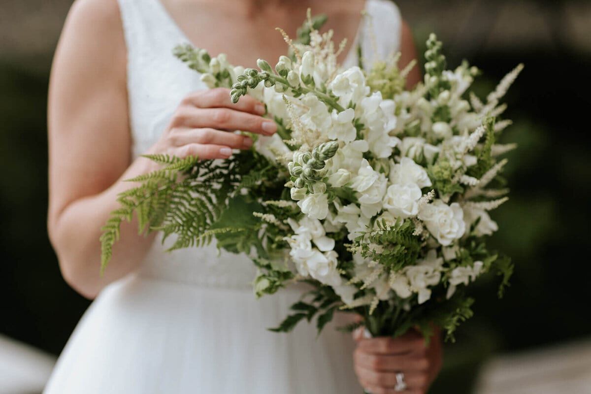 White snapdragon and fern bouquet held against a flowing gown