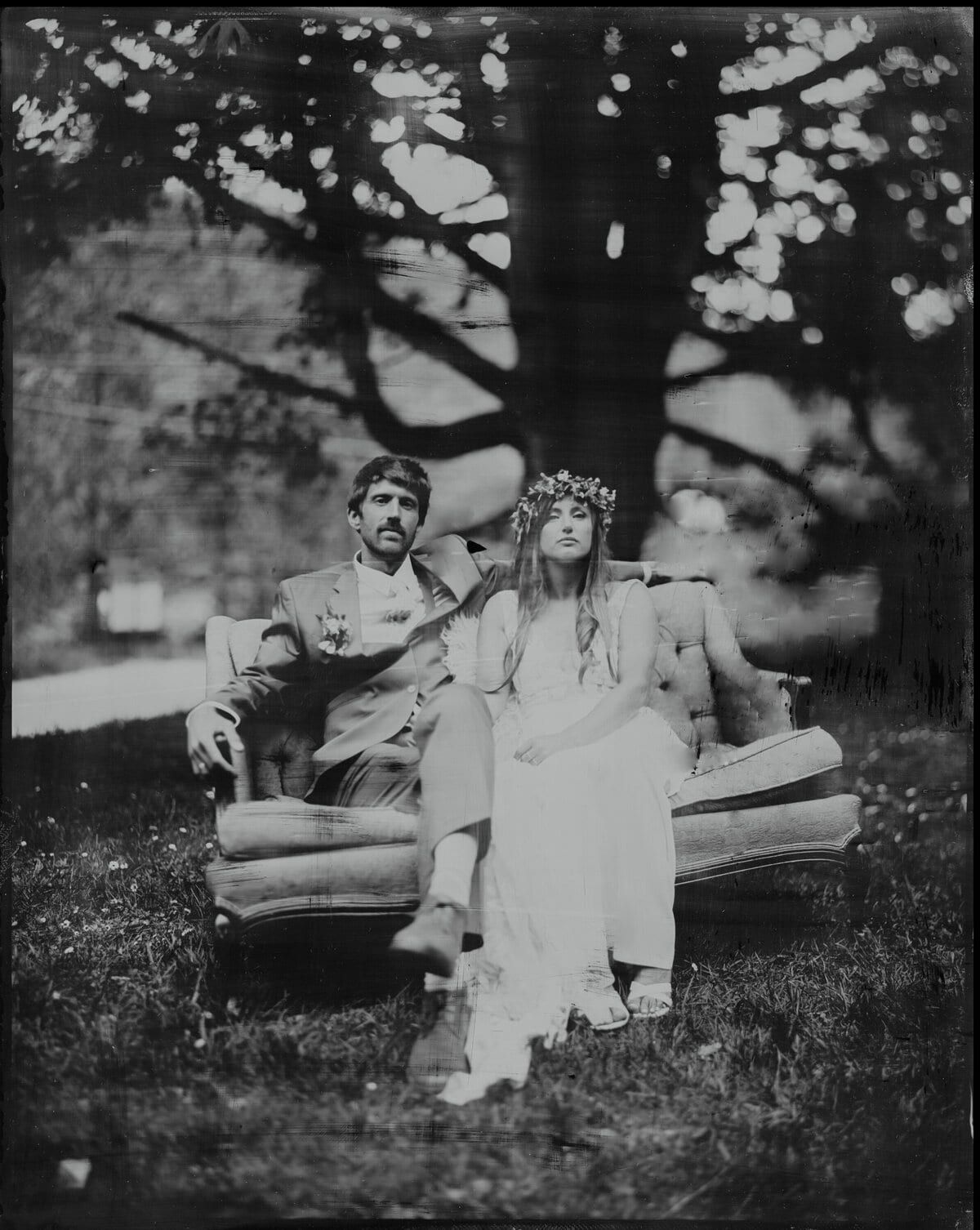 Flower-crowned bride and her groom lounging on an outdoor sofa