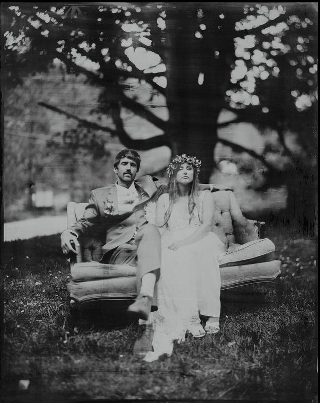 Flower-crowned bride and her groom lounging on an outdoor sofa