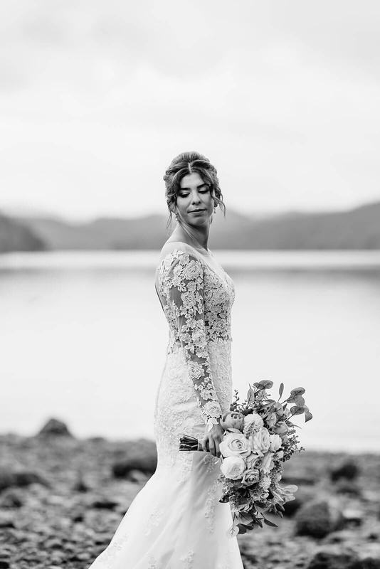 Black-and-white bride pausing with her bouquet at the lake's edge