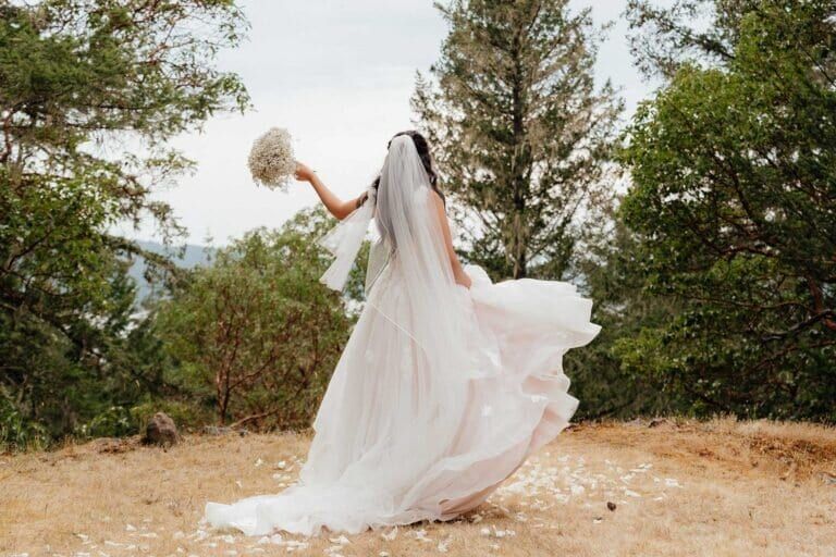 Bride swirling her gown on a hilltop clearing at Owl Grove