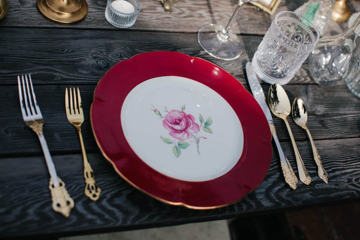 Crimson-rimmed rose plate set with ornate gold cutlery