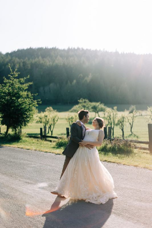 Couple dancing on a sunlit lane, gown sweeping the pavement