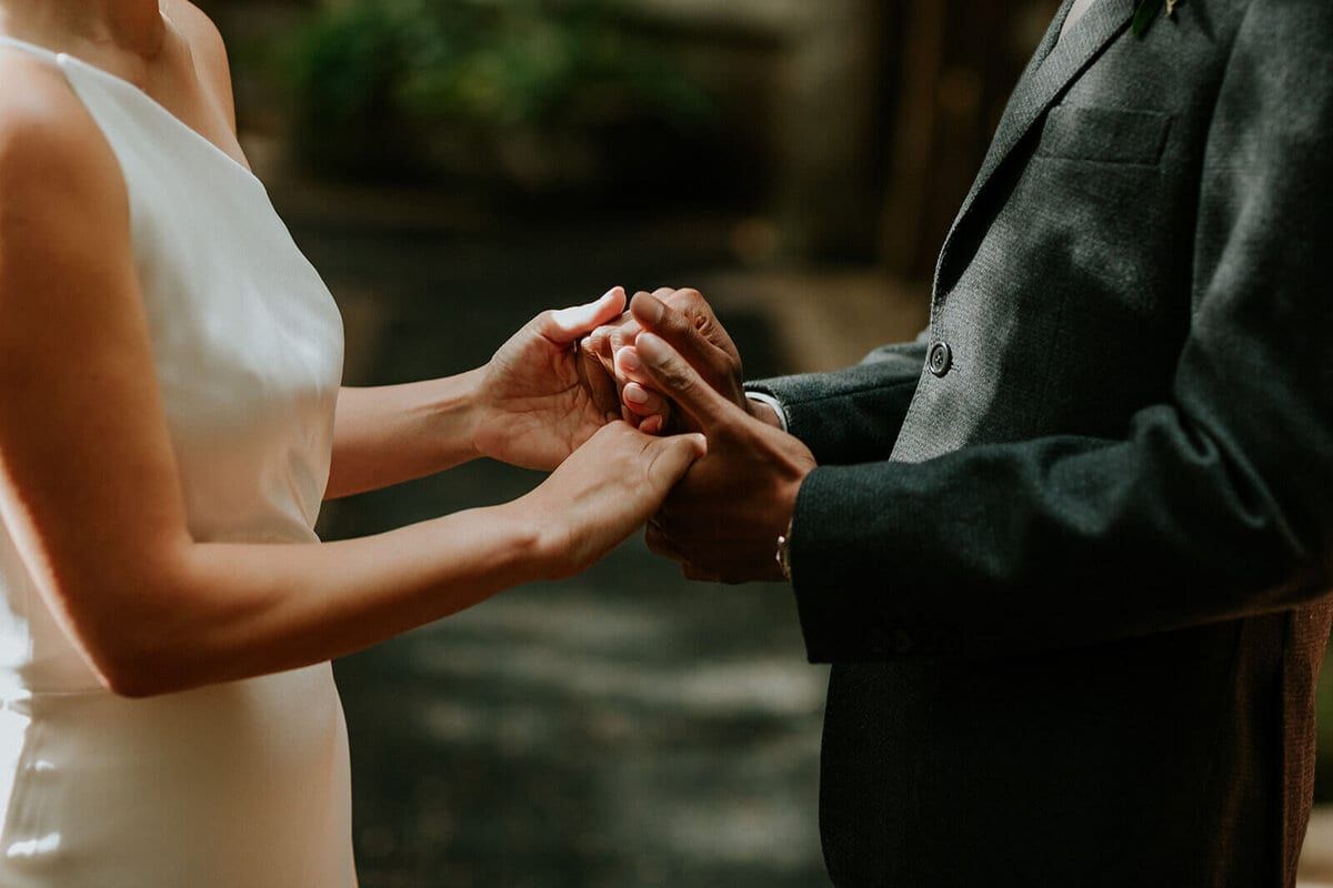 Close-up of a couple's clasped hands during their vows