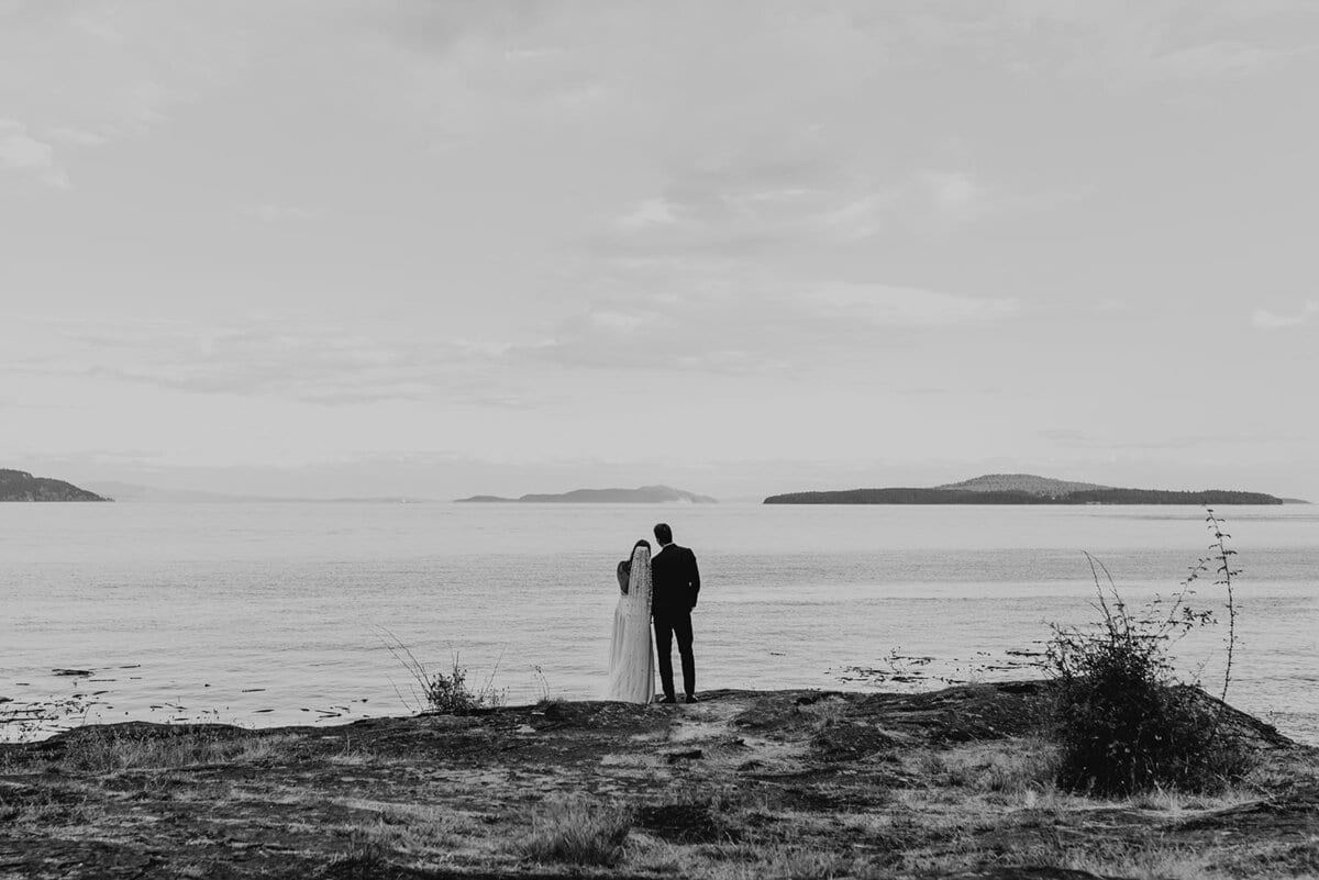 Distant newlyweds facing a calm sea dotted with islands