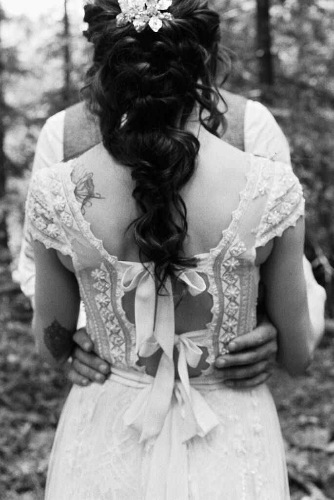 Black-and-white view of a bride's loose braid and lace corset back
