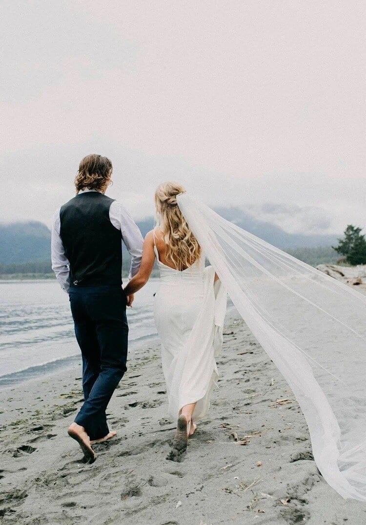 Newlyweds strolling the misty sand near Pacific Gateway Marina
