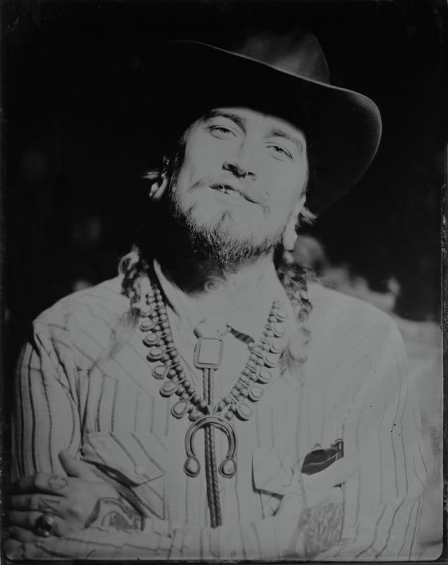 Grinning cowboy with braids and a silver squash-blossom necklace