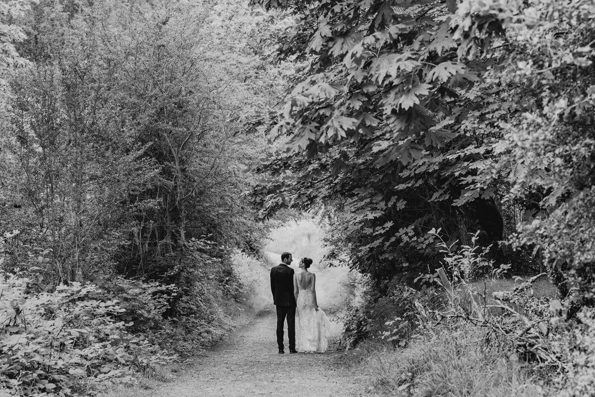 Couple strolling a shaded path beneath an arch of leaves