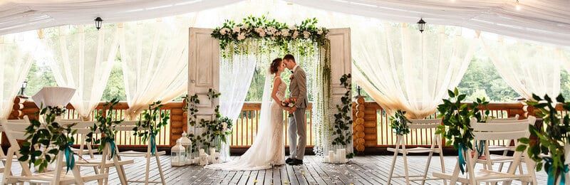 Couple kissing beneath a draped floral arch by Special Occasions