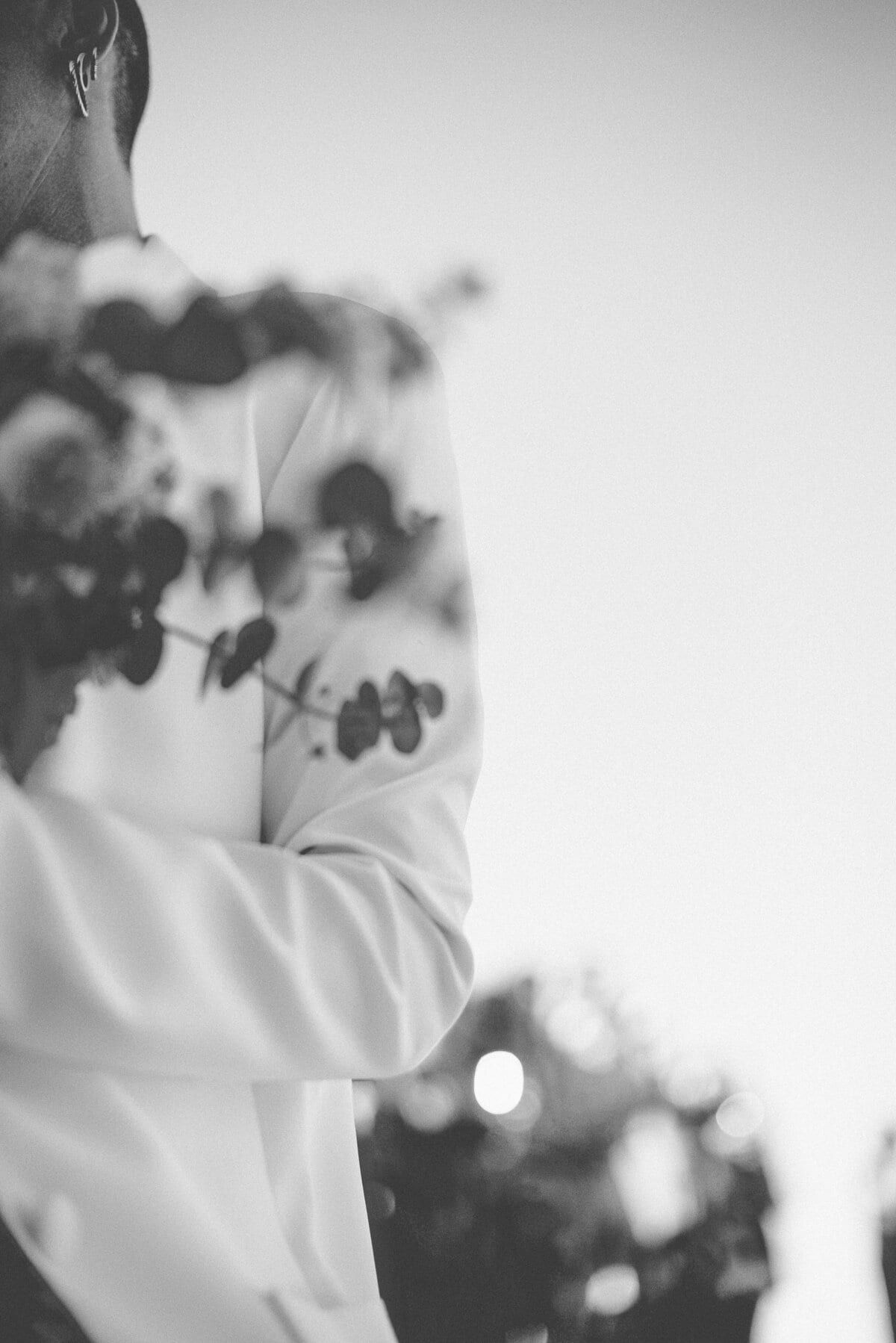 Black and white detail of eucalyptus over a white suit jacket