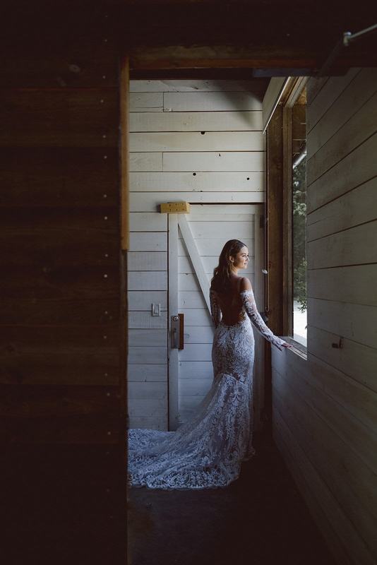 Bride with a long lace train looking out a cabin window