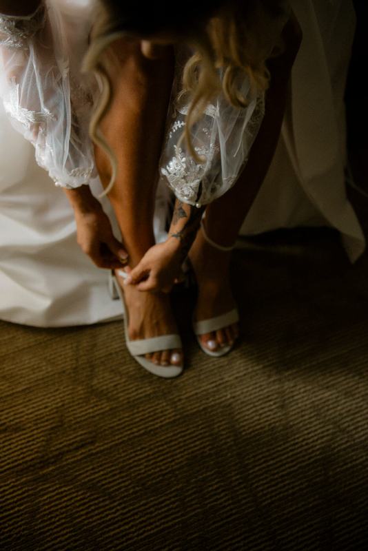 Bride fastening the strap of her white heeled sandal