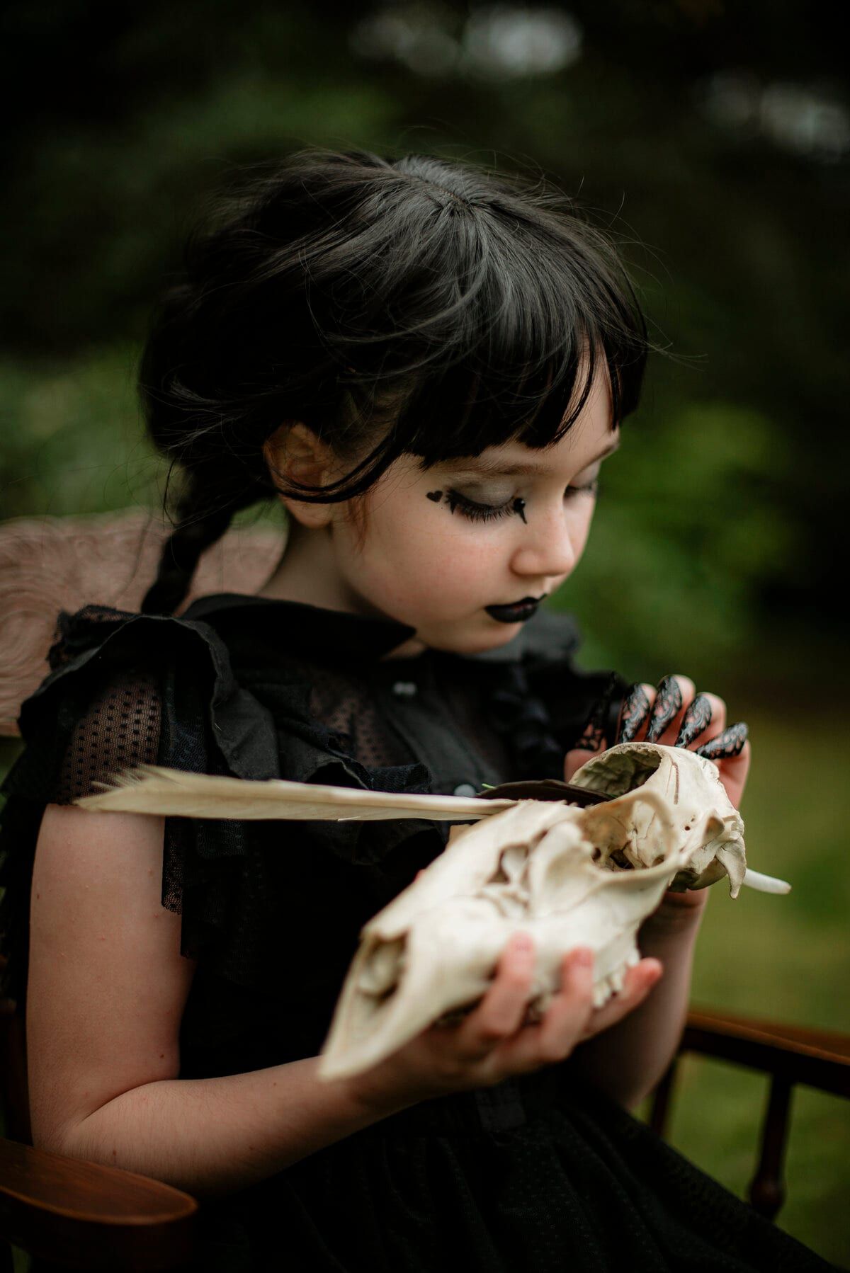 Costumed child with dark braids holding an animal skull and feather