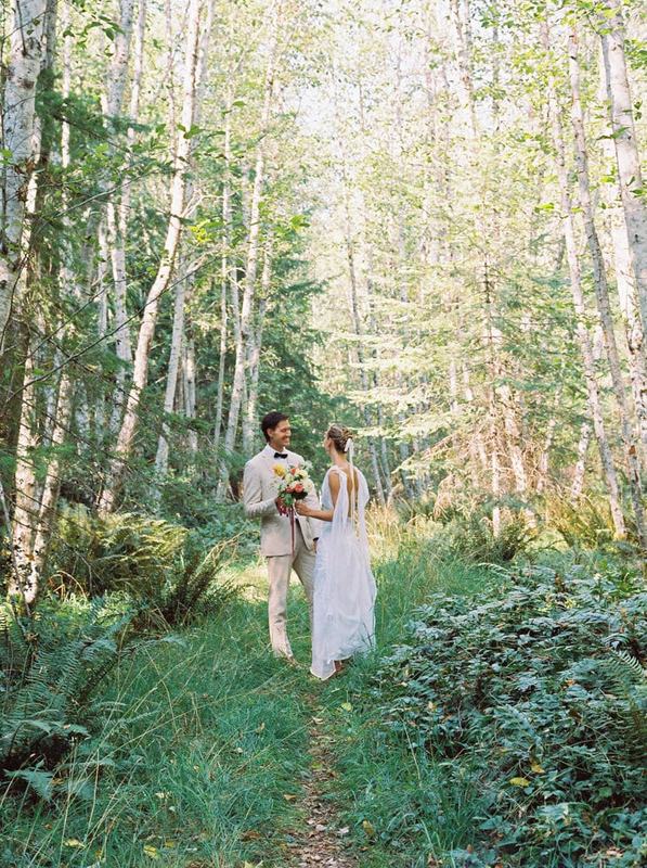 Newlyweds pausing on a narrow path through sunlit birch forest